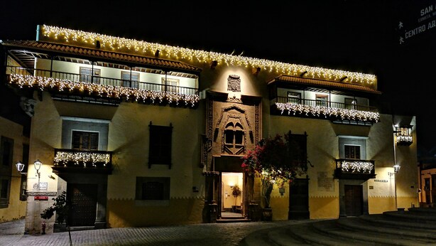 A historic building with a central entrance, balconies, and a cobblestone courtyard.