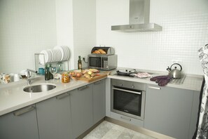A modern kitchen with a sink, microwave, oven, and a cutting board with vegetables. - Nice apartment Seville center with Free Parking (Sevilla)