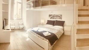 A modern bedroom with a large bed, a nightstand, a lamp, and a picture of the Colosseum on the wall. - Vatican Luxury Apartment (Rome)