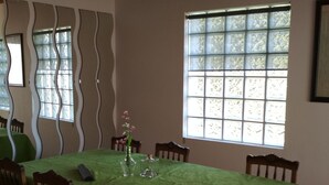 Un comedor con mantel verde, sillas de madera y una ventana con diseño de cuadrícula.