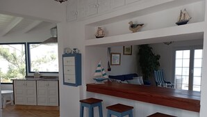 A kitchen with a wooden countertop, three blue stools, and decorative items including a ship and a bird.