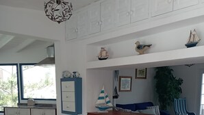 A kitchen with a wooden counter, three blue stools, a small table with a decorative item, and a window with a view of greenery.