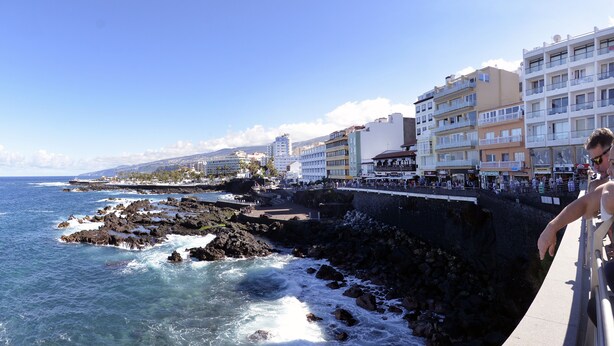 Una passeggiata lungomare con edifici, costa rocciosa e onde oceaniche.