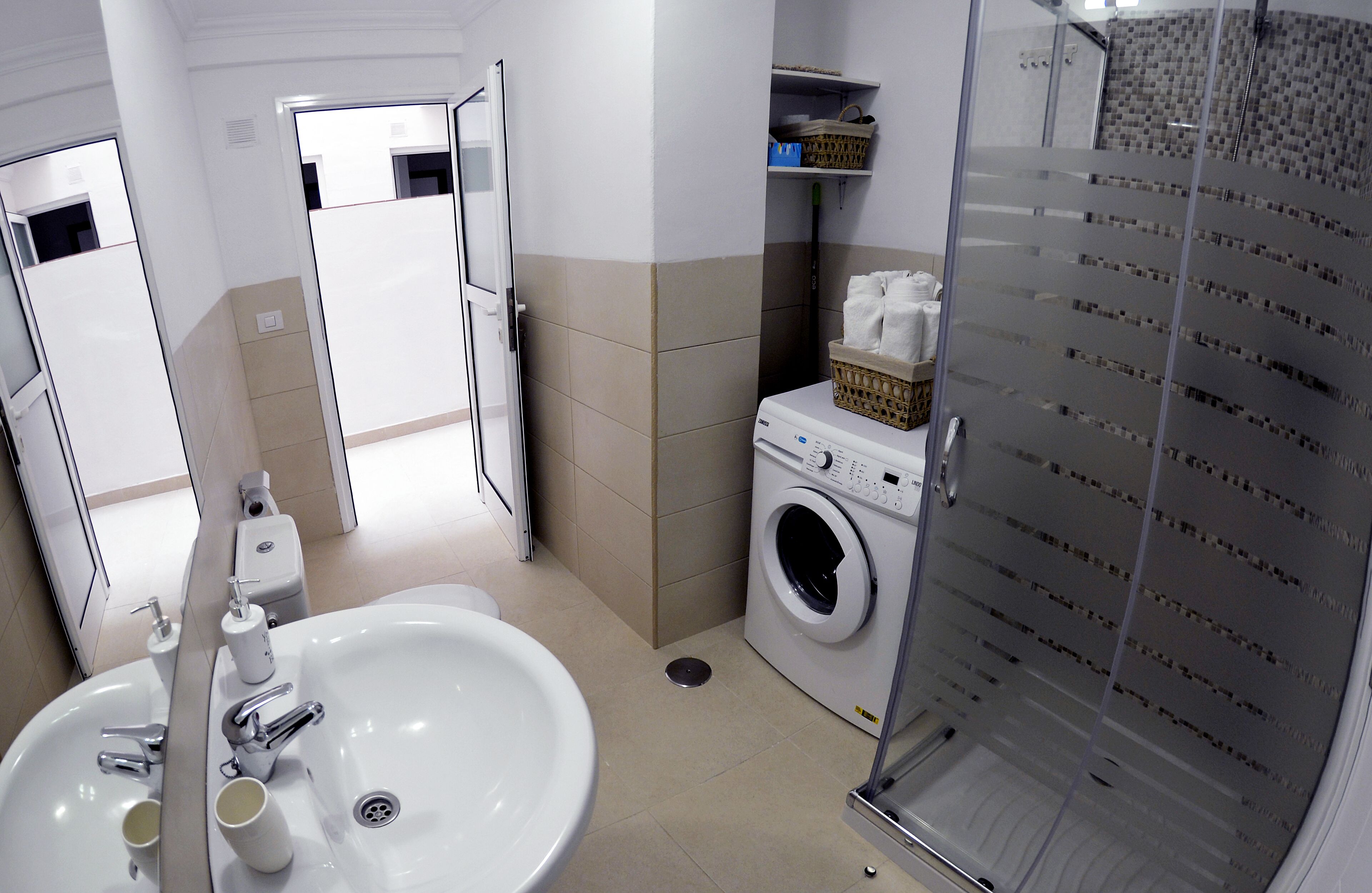 A bathroom with a sink, mirror, toilet, and a glass shower enclosure.