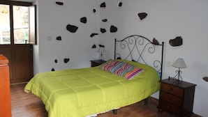 Una stanza con un letto, un comodino, una lampada e una porta in legno.