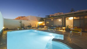 Una piscina con sillones de descanso y un área de terraza techada.