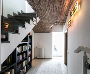 A modern interior with a staircase, bookshelves, and a radiator.
