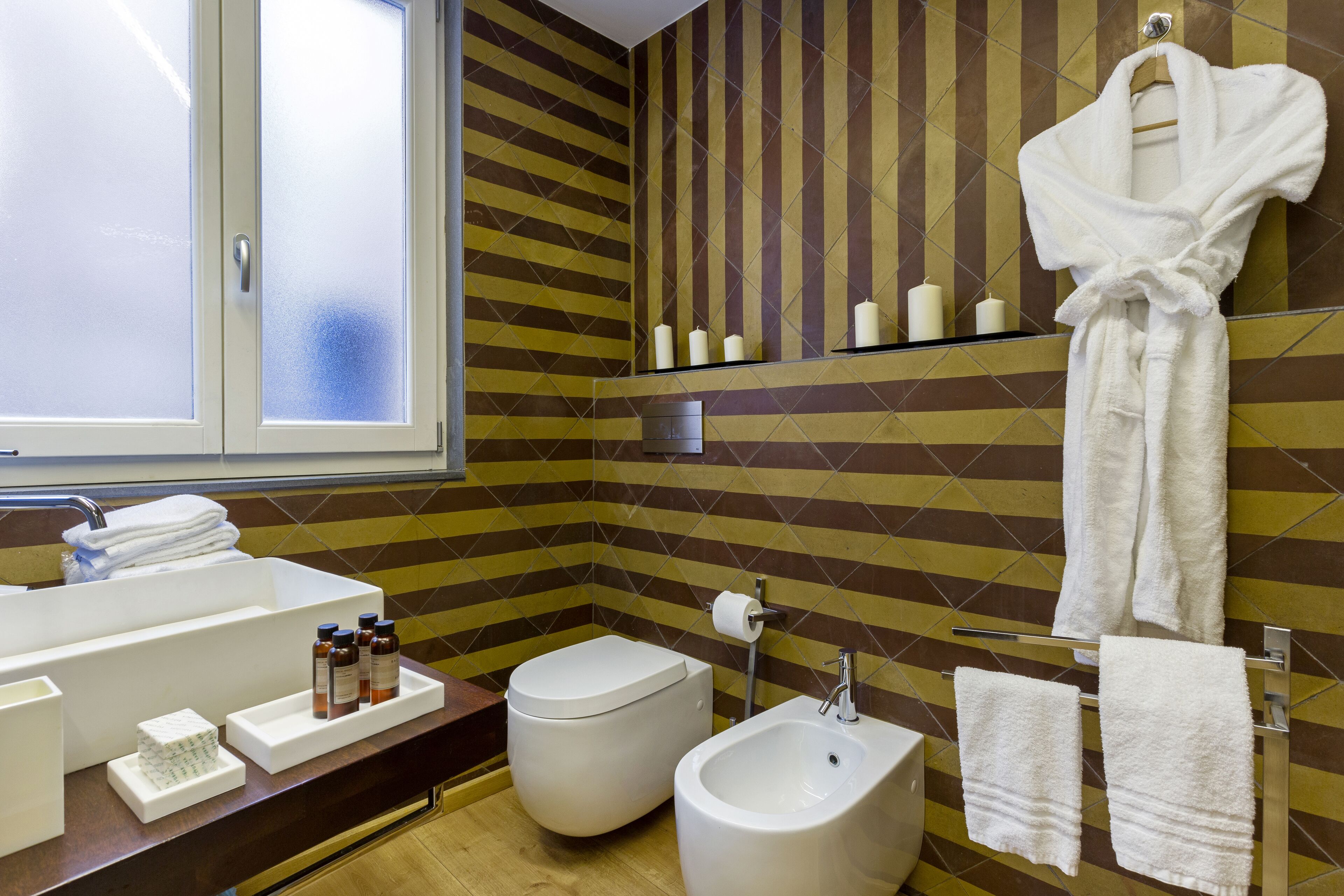 A bathroom with a sink, bidet, toilet, and a mirror with a towel rack.