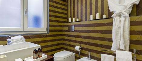A bathroom with a sink, bidet, toilet, and a mirror with a towel rack.