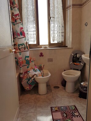 Een bad/douchecombinatie, een haardroger, een bidet, handdoeken
