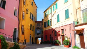 A narrow street with colorful buildings, a visible archway, and potted plants.