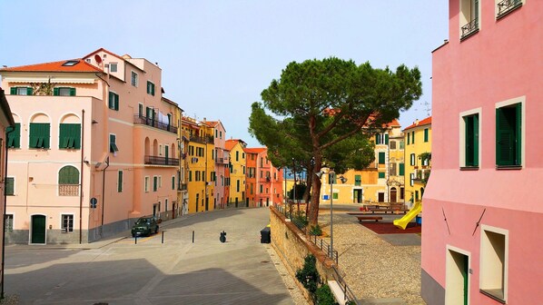 A street with colorful buildings, a tree, and a playground.