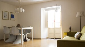 Une pièce comprenant une table à manger et des chaises, un canapé, une lampe et une porte donnant sur l’extérieur.