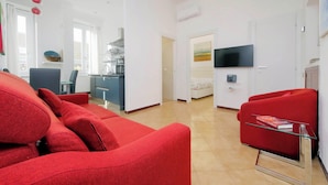 Un salon moderne avec des canapés rouges, une table basse en verre et un téléviseur à écran plat fixé au mur.