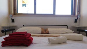 A neatly made bed with white and brown bedding, two bedside lamps, and a window with blinds. - A WINDOW ON THE SEA (Roccalumera (ME))