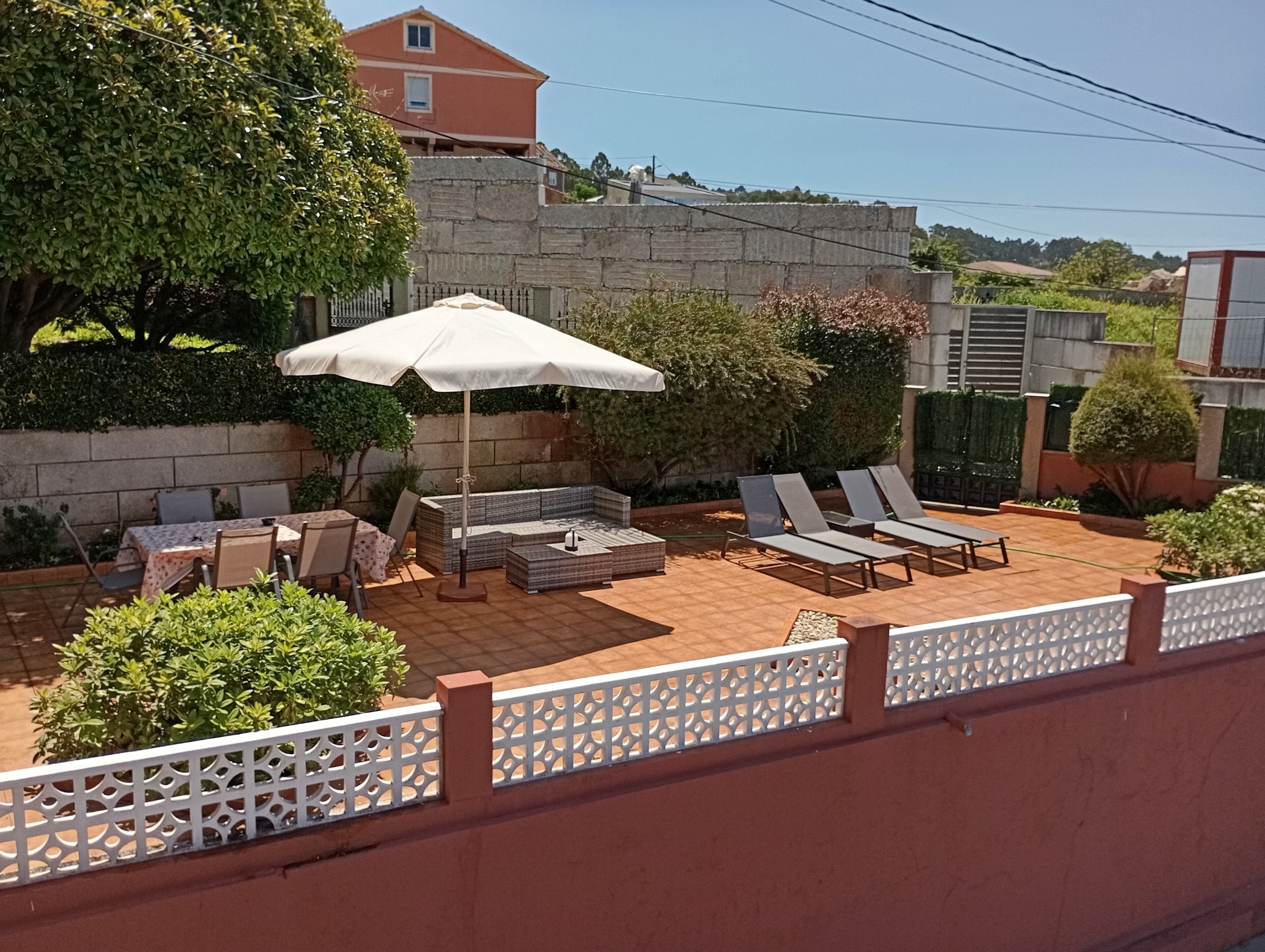Un espace patio aménagé avec des sièges, une table et un parasol.