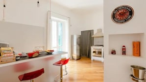 A modern kitchen with a bar area, a refrigerator, and a clock on the wall. - Bijoux Luxury Apartment in Old Town (Bari)