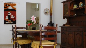 A dining area with a wooden table and chairs, a decorative tapestry, a vase with flowers, and a cabinet with pottery. - Comfortable apartment for exclusive use (Valderice)
