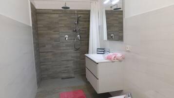Ein modernes Badezimmer mit Dusche, Waschbecken und Spiegel.