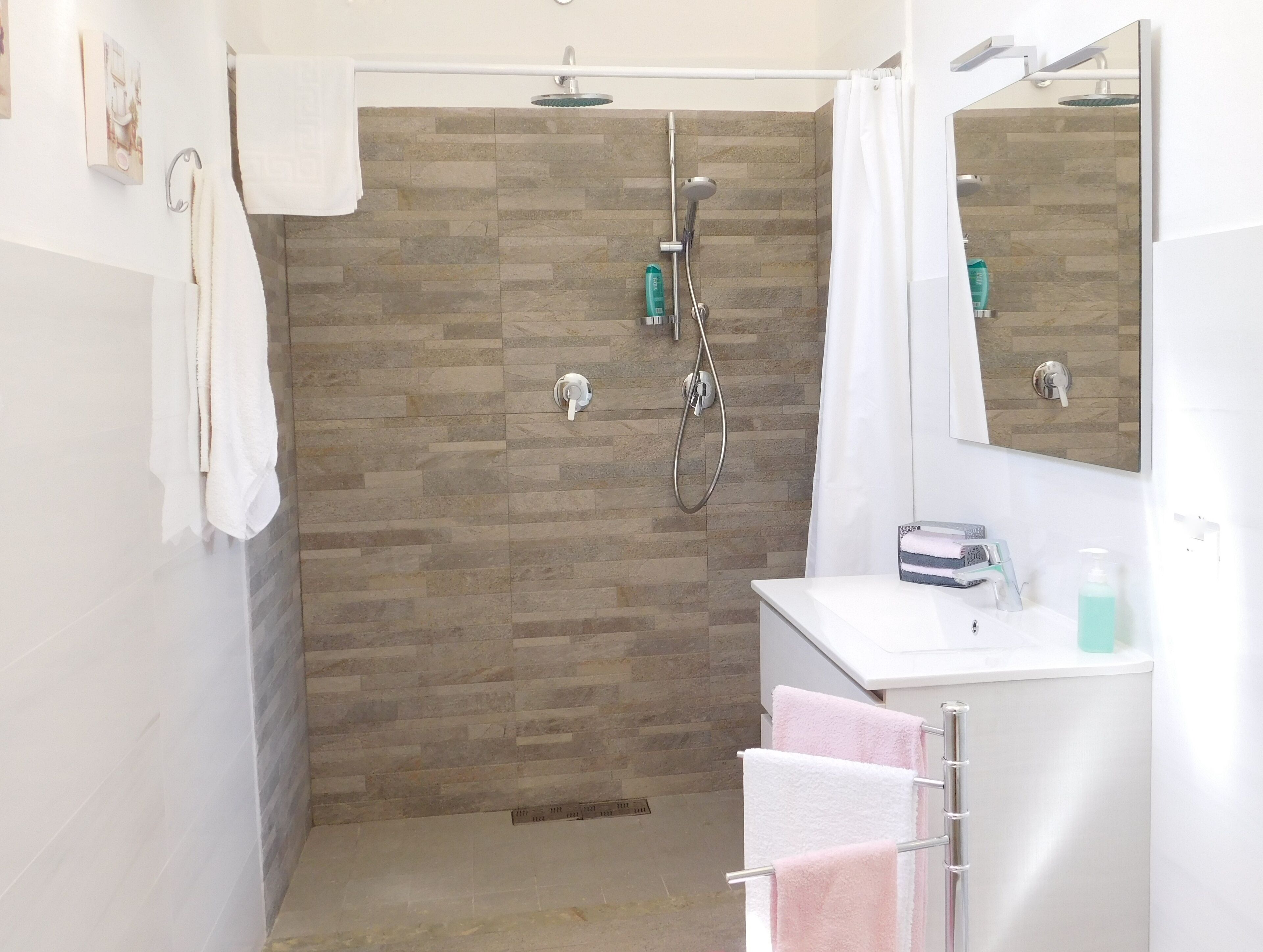 Une salle de bain moderne avec une douche, un lavabo blanc et un miroir.