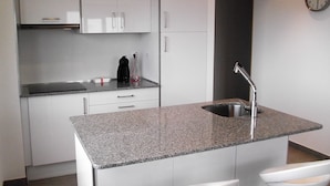 A modern kitchen with white cabinets, a granite countertop, a stainless steel sink, and a clock on the wall. - Barrañan beach apartments, Apartment 22 (Arteixo)