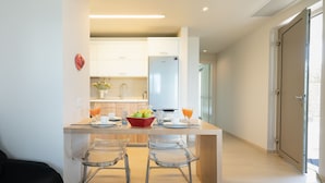 Een moderne keuken met een centraal eiland, barstoelen en een koelkast.