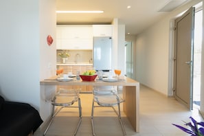 A modern kitchen with a central island, bar stools, and a refrigerator.
