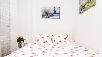 Een slaapkamer met een bed, een vaas met bloemen en een schilderij aan de muur.