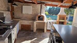 An outdoor kitchen area with a stone wall, a pizza oven, and a grill. - LA MAISON DU MOULIN DE TARTAY EN AVIGNON (Avignon)