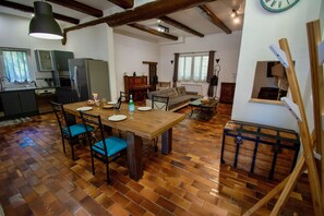 A spacious living area with a wooden dining table, blue cushioned chairs, a sofa, and a rustic wooden chest. - LA MAISON DU MOULIN DE TARTAY EN AVIGNON (Avignon)