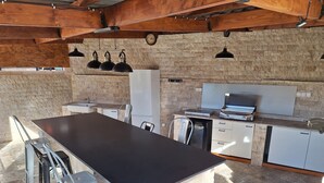 A kitchen with a large island, white cabinets, and a built-in grill. - LA MAISON DU MOULIN DE TARTAY EN AVIGNON (Avignon)