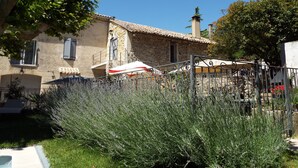 A stone building with a tiled roof, a staircase, and a garden with lavender plants. - LA MAISON DU MOULIN DE TARTAY EN AVIGNON (Avignon)