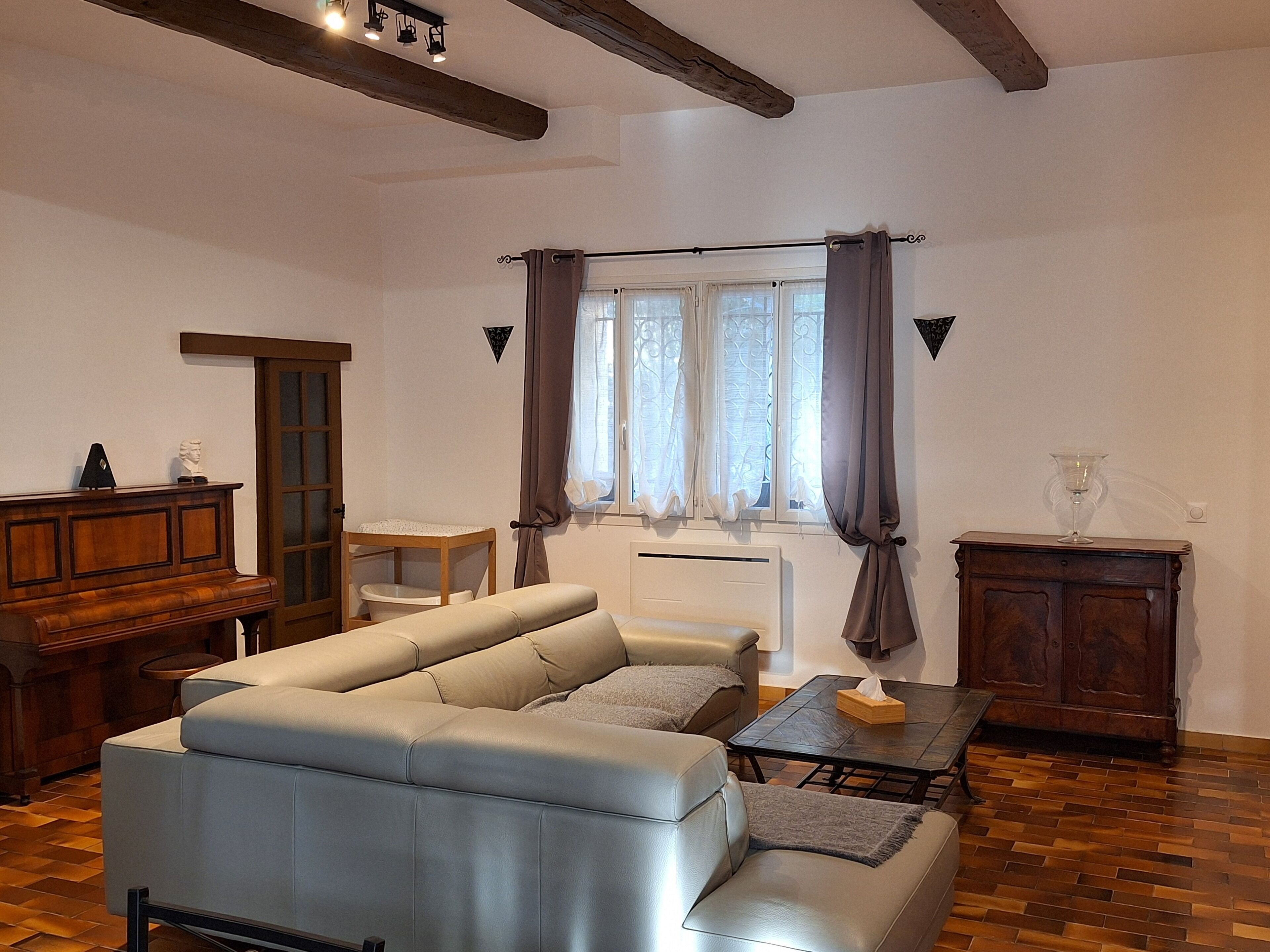 A living room with a sofa, a wooden cabinet, a table, and a window with curtains.