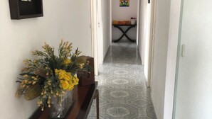 A hallway with patterned floor tiles, a wooden console table with a vase of yellow flowers, and a framed picture on the wall. - Single-storey house 125 m² facing the sea, patio with barbecue and garden. (Crozon)