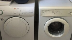A laundry area with two washing machines, a shelf with folded towels, and a container with cleaning supplies. - Single-storey house 125 m² facing the sea, patio with barbecue and garden. (Crozon)