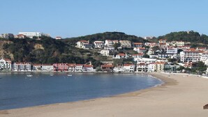 A coastal town with a sandy beach, buildings along the shore, and boats in the water. - Farmhouse with large outdoor garden, private, near the beach, very green and quiet (Alfeizerão - São MArtinho do porto)