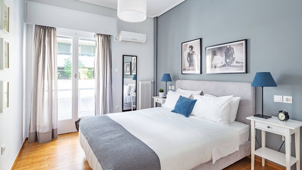 Un dormitorio moderno con una cama grande, mesitas de noche, un radiador y obras de arte en la pared.