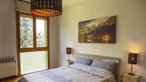 Une chambre à coucher avec un grand lit, deux lampes de chevet, une fenêtre et un tableau au mur.
