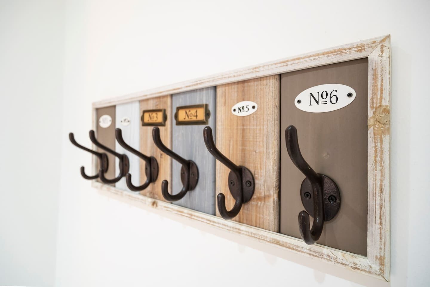 Ein an der Wand befestigter Garderobenständer mit beschrifteten Haken, jeder Haken mit einer Nummer versehen.