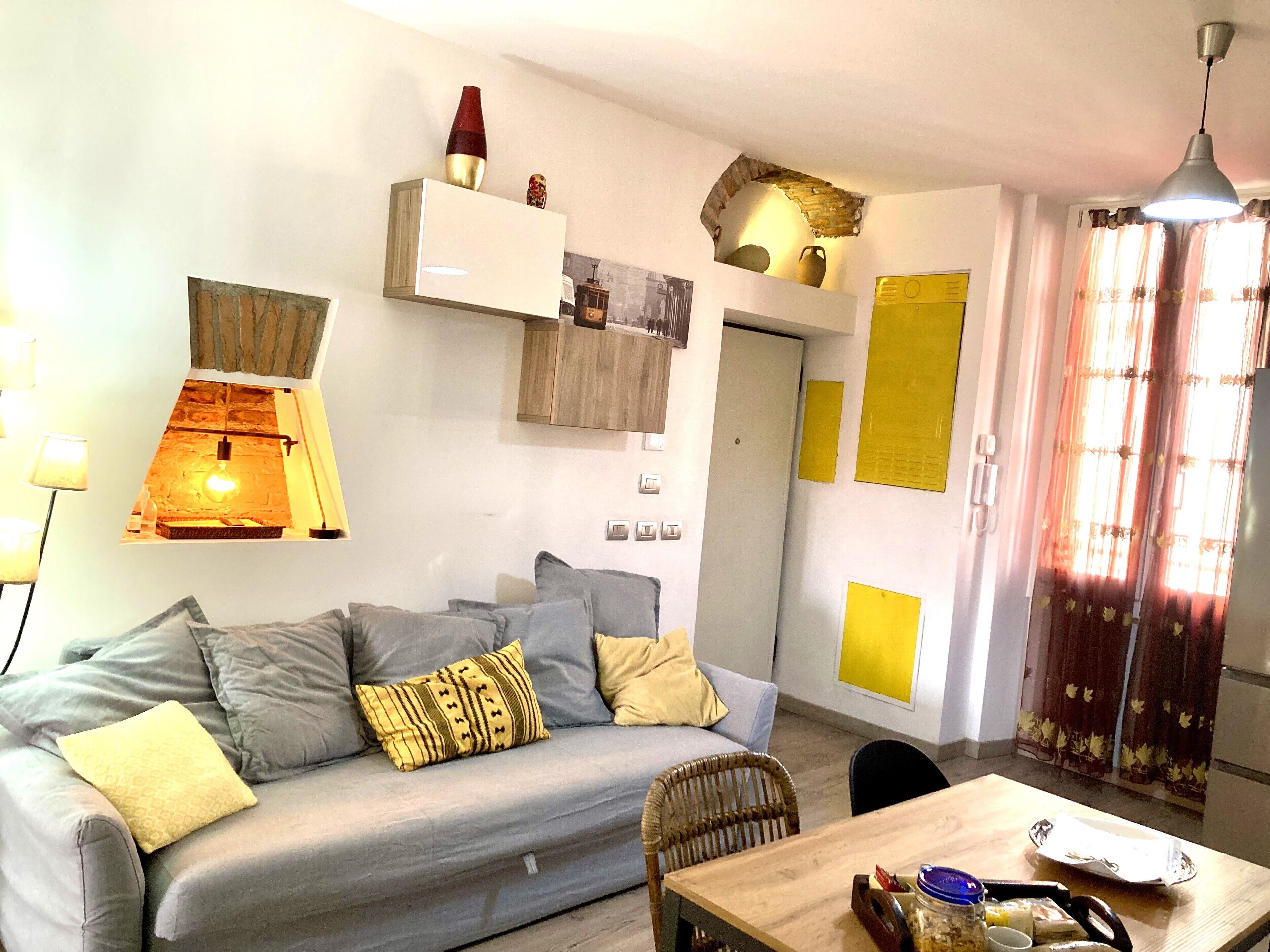 Un soggiorno moderno con un divano, un tavolo da pranzo in legno e una lampada a sospensione.