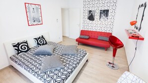 A modern bedroom with a patterned bed, a red sofa, a red chair, and a wall with circular patterns. - Vintage Apartment Trastevere St. (Roma)