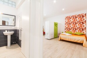 A modern hotel room with a bathroom, a bed, and a patterned wall.