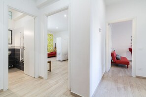 Een hal met een badkamer, een bed en een rode stoel.