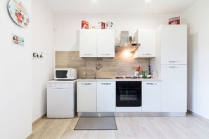Une cuisine moderne avec des meubles blancs, un four à micro-ondes, un lave-vaisselle, un four et un évier.