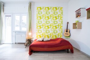 Een slaapkamer met een bed, een gitaar en een raam met gordijnen.