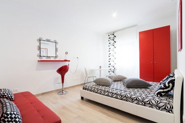 A modern bedroom with a bed, red wardrobe, and a red chair.