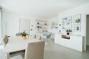 A modern, minimalist living space with a dining area, kitchen, and a small seating area. - Apartment a stone's throw from the lake (Valcanover)