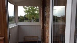 Un petit balcon fermé, avec un banc en bois, une fenêtre et une porte.