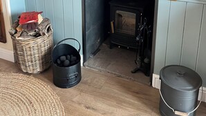 Une pièce avec une cheminée, un panier en osier, un seau noir et un tapis rond tissé.