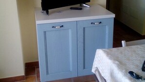 Een kamer met een televisie op een kast, een tafel met een witte tafelkleed en een stoel.